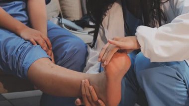 Genç bir Asyalı kadın, bir sağlık sorununu vurgulamak için hastanede ayağını doktora gösteriyor.