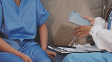 Beyaz üniformalı doktor klinikteki hastalarla sağlık sorunlarını tartışıyor.