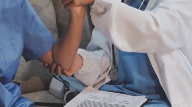 Beyaz üniformalı genç doktor hastaya hastanede el egzersizi yaptırmaya yardım ediyor.