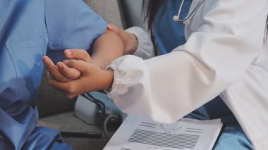 Beyaz üniformalı genç doktor hastaya hastanede el egzersizi yaptırmaya yardım ediyor.