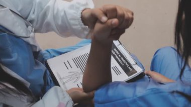 Beyaz üniformalı genç doktor hastaya hastanede el egzersizi yaptırmaya yardım ediyor.