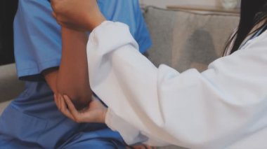 Beyaz üniformalı genç doktor hastaya hastanede el egzersizi yaptırmaya yardım ediyor.