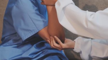 Beyaz üniformalı genç doktor hastaya hastanede el egzersizi yaptırmaya yardım ediyor.