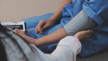 Kanepede kadının tansiyonunu ölçmeye yardım eden Asyalı doktor.