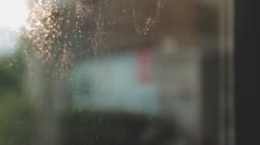 Modern ofisin penceresinden suyu silmek için Squeegee kullanan Asyalı kadın.