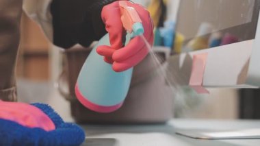 Bilgisayar masasını paçavrayla temizleyen genç bir kadının yakın plan görüntüsü.
