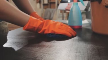 Lastik eldivenli kadın masasını temizliyor.