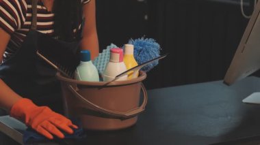 Önlüklü genç bayan işçi mutfakta bez parçasıyla evi temizliyor.