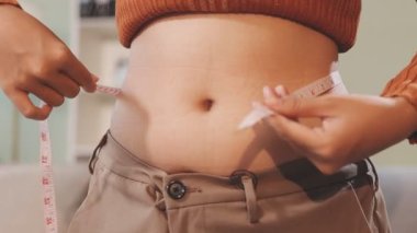 Hamile bir kadın karnını evde ölçüyor. Karnını ölçen hamile bir kadın..