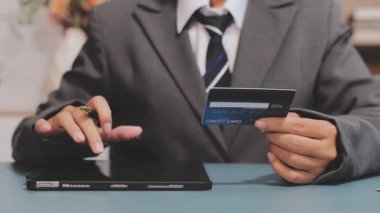 Asyalı takım elbiseli genç iş kadınının kredi kartı numarasını tablete girerken yakın plan görüntüsü.