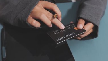 Asyalı takım elbiseli genç iş kadınının kredi kartı numarasını tablete girerken yakın plan görüntüsü.