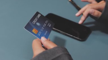 Takım elbiseli genç bayan kredi kartı numarasını telefona girerken yakın plan görüntüsü.
