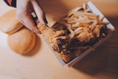 Odaklan kadın. Elin kızarmış tavuğu yemek için tutuyor. Fast food konsepti olan bir kız.