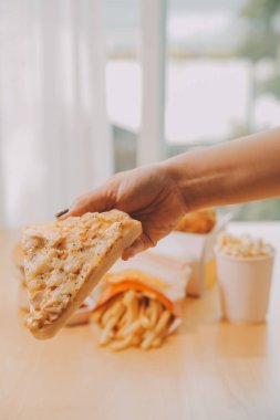 Restoranda pizza dilimi tutan bir kadın resmi.