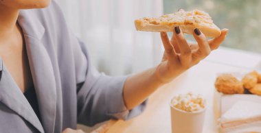 Restoranda pizza dilimi tutan bir kadın resmi.