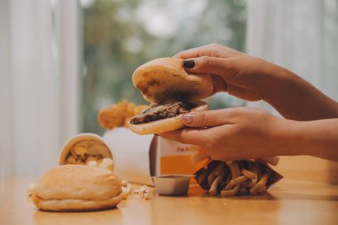 lokanta, insanlar ve sağlıksız beslenme kavramı - yakın çekim kadın elinde hamburger ya da çizburger tutarak