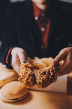 Odaklan kadın. Elin kızarmış tavuğu yemek için tutuyor. Fast food konsepti olan bir kız.