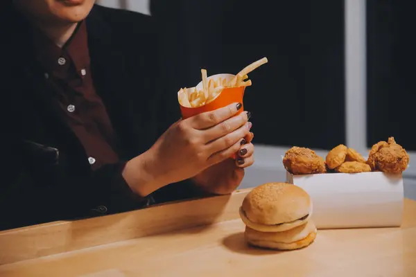 stock image Asian woman holding french fries and eating happily in restaurant