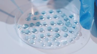 Genç bayan araştırmacı modern bir laboratuarda kimyasal sıvıları yakından inceliyor..