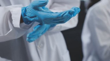 Yakın çekim. Koruyucu eldivenli doktorlar hastane odasında duruyor.