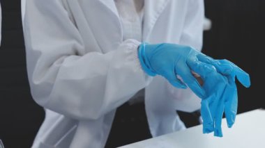 Koruyucu kıyafetli bilim adamı laboratuarda bir deney tüpü tutuyor..