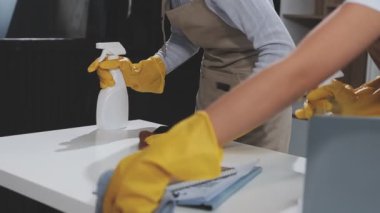 Sarı lastik eldivenli kadın eli yere sprey sıkılmış.