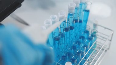 Bilim adamı laboratuarda sıvı tüpü tutuyor.