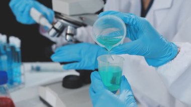 Koruyucu eldivenlerdeki bilim adamı laboratuarda sıvı içeren tüpü tutuyor.