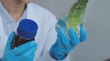 Örnek şişedeki Sağlıklı Yeşil Bitki 'ye bakan bir mikrobiyolog. Gelişmiş Teknoloji Mikroskopları ve Bilgisayarlarıyla Modern Gıda Bilimleri Laboratuvarında çalışan bir tıp bilimcisi.