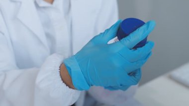 Doktor eli mavi eldivenli, elinde bir test tüpü tutuyor.