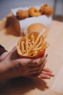 Asyalı kadın elinde patates kızartması ve restoranda mutlu bir şekilde yemek yiyor.