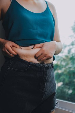 Şişman kadın, şişko, obez kadın el ele tutuşan ölçü bandıyla göbek yağı, kadın diyeti yaşam tarzı konsepti