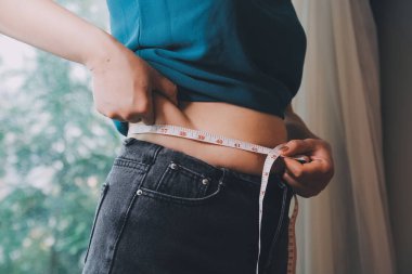 Şişman kadın, şişko, obez kadın el ele tutuşan ölçü bandıyla göbek yağı, kadın diyeti yaşam tarzı konsepti