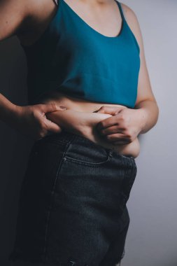 Şişman kadın, şişko, obez kadın el ele tutuşan ölçü bandıyla göbek yağı, kadın diyeti yaşam tarzı konsepti