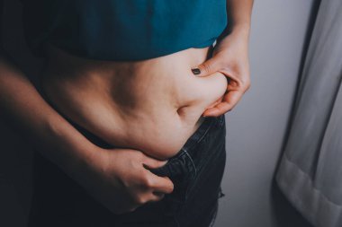 Şişman kadın, şişko, obez kadın el ele tutuşan ölçü bandıyla göbek yağı, kadın diyeti yaşam tarzı konsepti