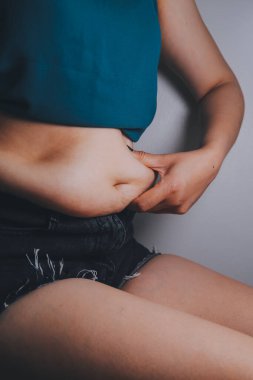 Şişman kadın, şişko, obez kadın el ele tutuşan ölçü bandıyla göbek yağı, kadın diyeti yaşam tarzı konsepti