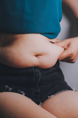 Şişman kadın, şişko, obez kadın el ele tutuşan ölçü bandıyla göbek yağı, kadın diyeti yaşam tarzı konsepti