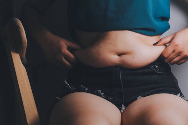 Şişman kadın, şişko, obez kadın el ele tutuşan ölçü bandıyla göbek yağı, kadın diyeti yaşam tarzı konsepti