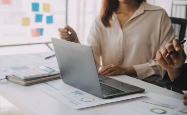 Finansal analistler, şirketlerin başarılı takım çalışmalarının sonuçlarını gösteren bir toplantıda bir dijital tablet planlama yatırım projesinin ticari mali raporlarını analiz ediyorlar..