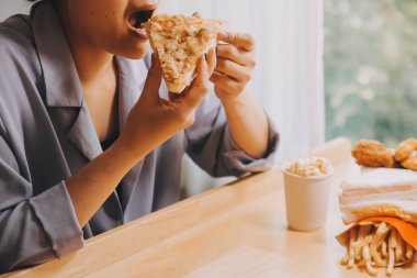 Restoranda pizza dilimi tutan bir kadın resmi.