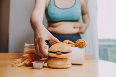 Yemek ya da değil. Burger bakarak cheerless tombul kadın yemek ya da değil düşünme