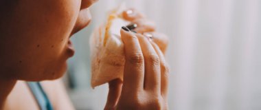 Asyalı sağlıklı bir kadın sabah sandviçle kahvaltı yapar.