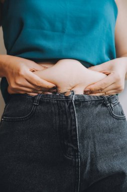 Şişman kadın, şişko, obez kadın el ele tutuşan ölçü bandıyla göbek yağı, kadın diyeti yaşam tarzı konsepti