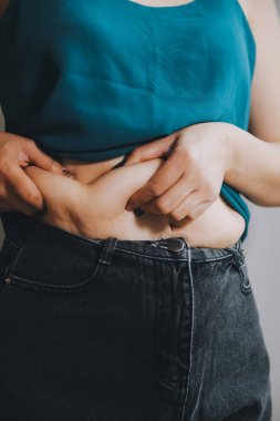 Şişman kadın, şişko, obez kadın el ele tutuşan ölçü bandıyla göbek yağı, kadın diyeti yaşam tarzı konsepti