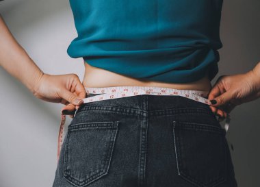 Şişman kadın, şişko, obez kadın el ele tutuşan ölçü bandıyla göbek yağı, kadın diyeti yaşam tarzı konsepti