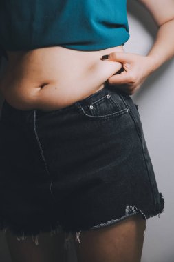 Şişman kadın, şişko, obez kadın el ele tutuşan ölçü bandıyla göbek yağı, kadın diyeti yaşam tarzı konsepti