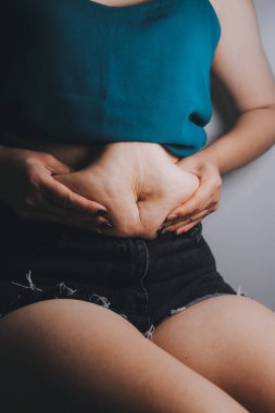 Şişman kadın, şişko, obez kadın el ele tutuşan ölçü bandıyla göbek yağı, kadın diyeti yaşam tarzı konsepti