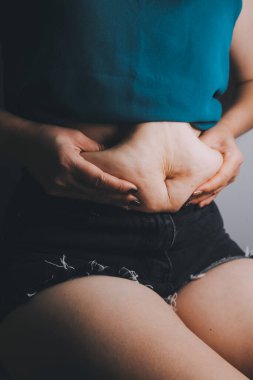 Şişman kadın, şişko, obez kadın el ele tutuşan ölçü bandıyla göbek yağı, kadın diyeti yaşam tarzı konsepti