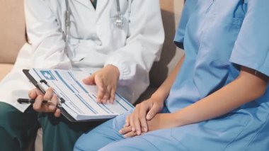 Steteskop tutan ve gülümseyen üniformalı genç Asyalı doktor..