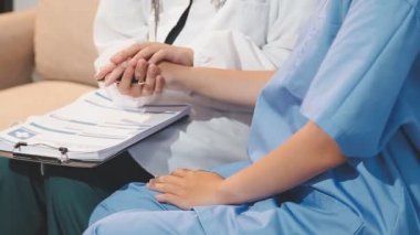 Hastane ofisinde el ele tutuşan doktor, hasta bakımı ve sağlık konsepti.